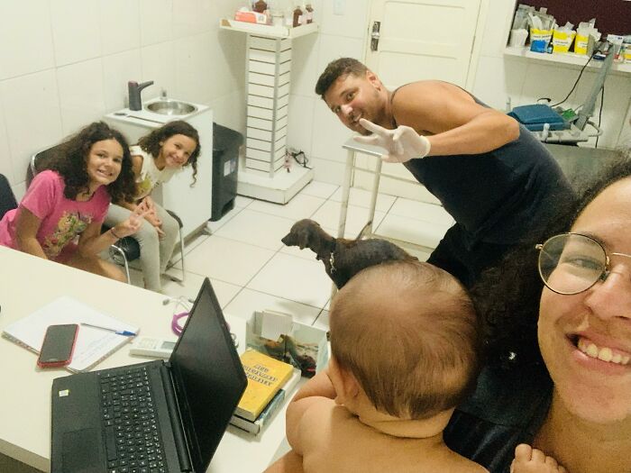 Family with a stray dog in a cozy room; two children smiling, an adult holding a baby, and one man posing cheerfully.