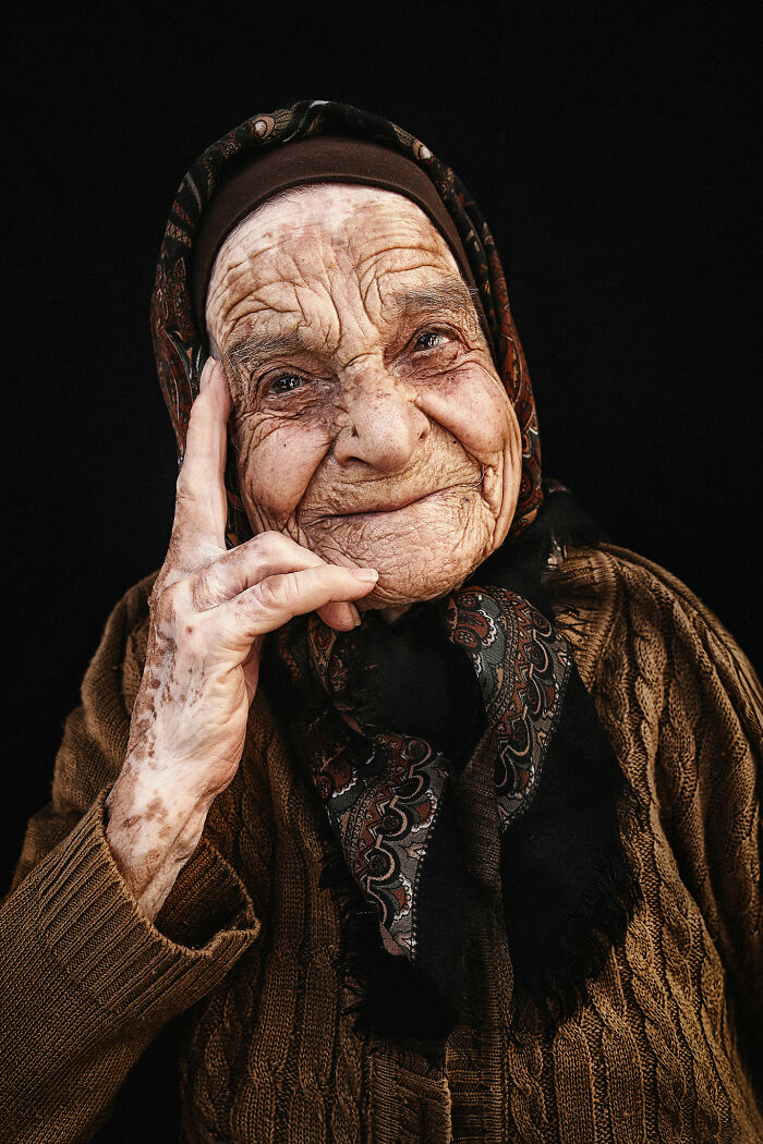 Portrait of an elderly woman with a headscarf, showing expressive facial features.