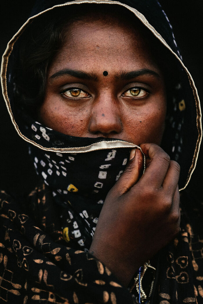 Portrait of a person with expressive eyes, covered partially with a patterned scarf, showcasing captivating facial expression.