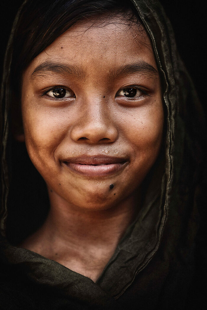 Expressive face of a young person in close-up, wearing a dark hood, captured by a photographer.