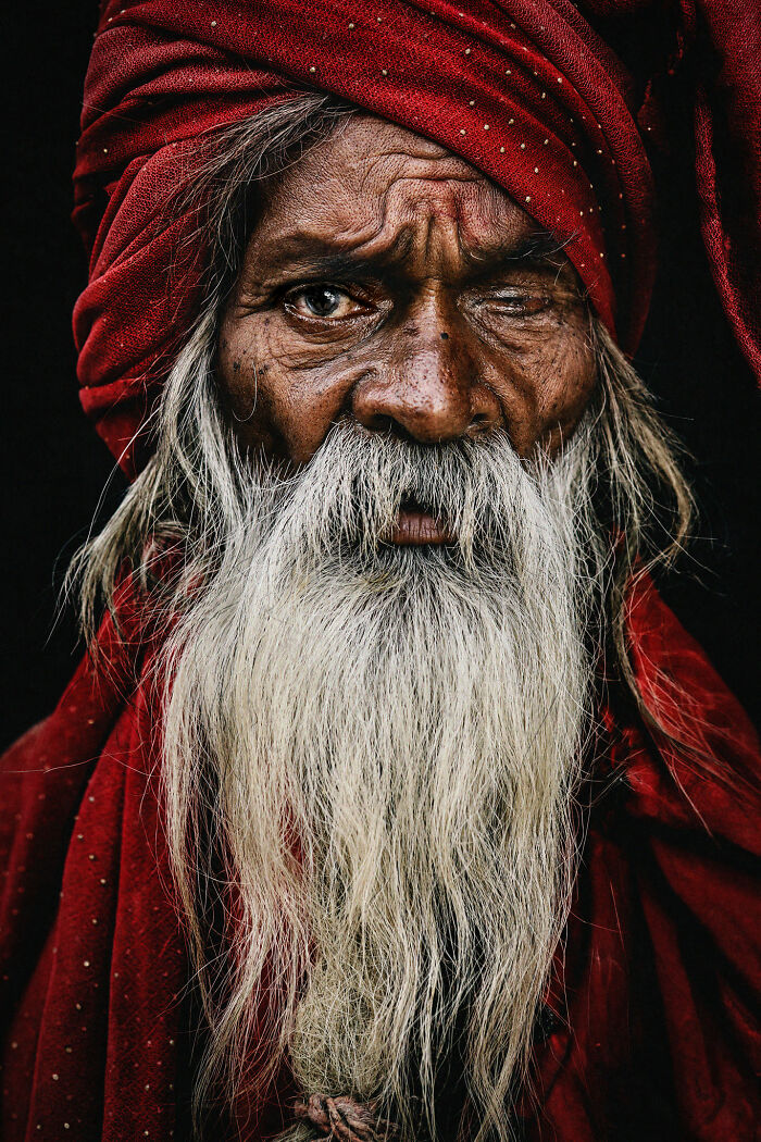 Photographer captures an expressive face with weathered features and a red turban, telling its own story.
