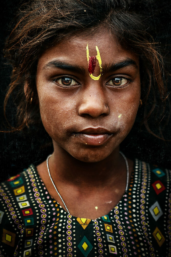 Expressive face of a young girl with vibrant eyes and colorful markings, captured by a photographer.