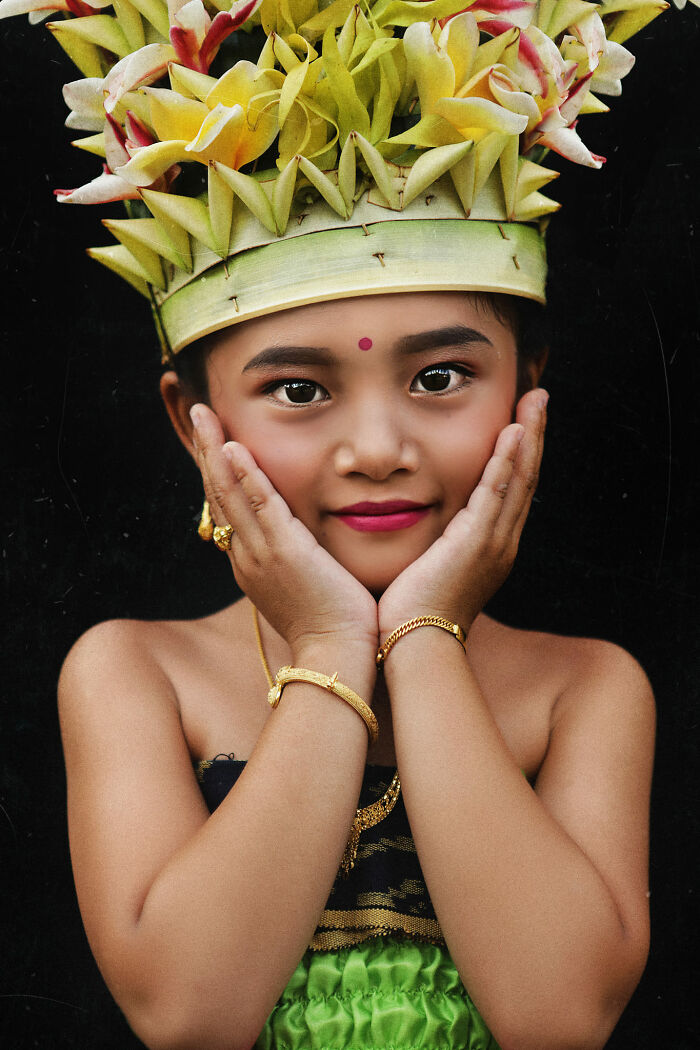 Expressive face of a young girl in traditional attire, wearing a floral headdress and jewelry, showcasing a cultural story.