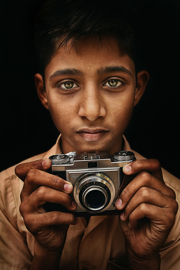 Expressive face of a young photographer holding a vintage camera, highlighting emotion and storytelling through photography.