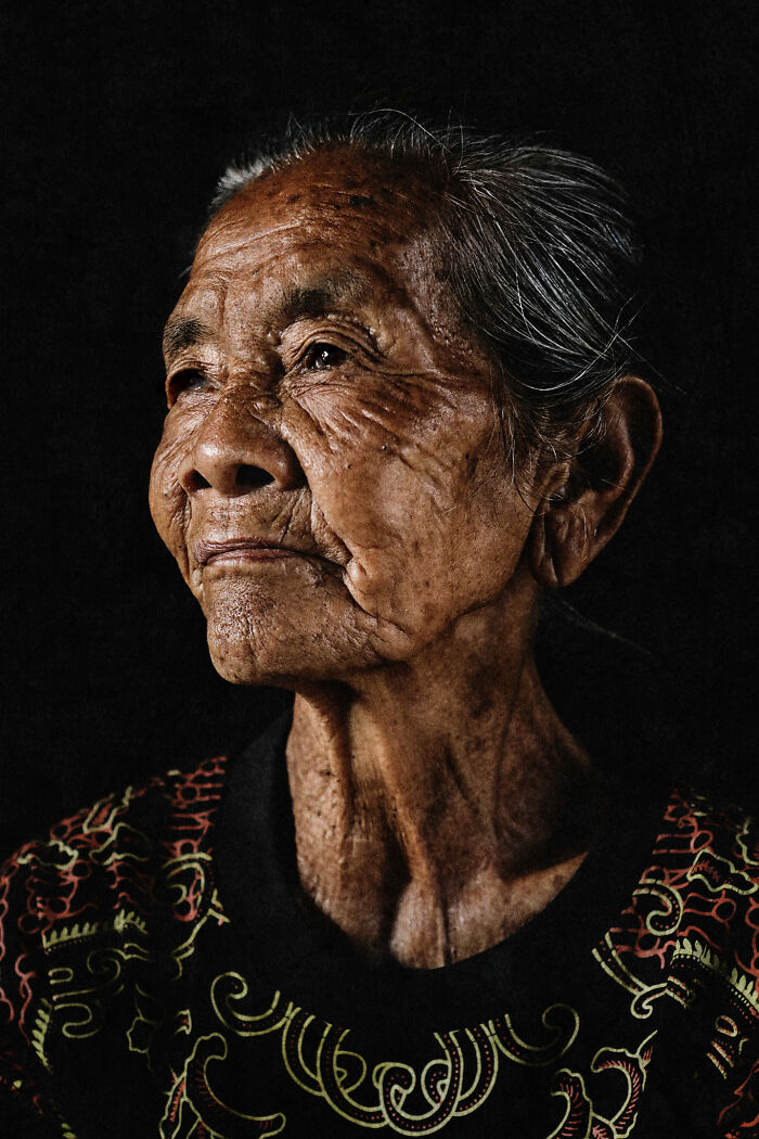 Photographer captures expressive elderly woman's face in a detailed portrait against a dark background.