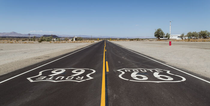 Open road intersection with Route 66 and Route 99 signs, iconic symbols of legendary American road routes.