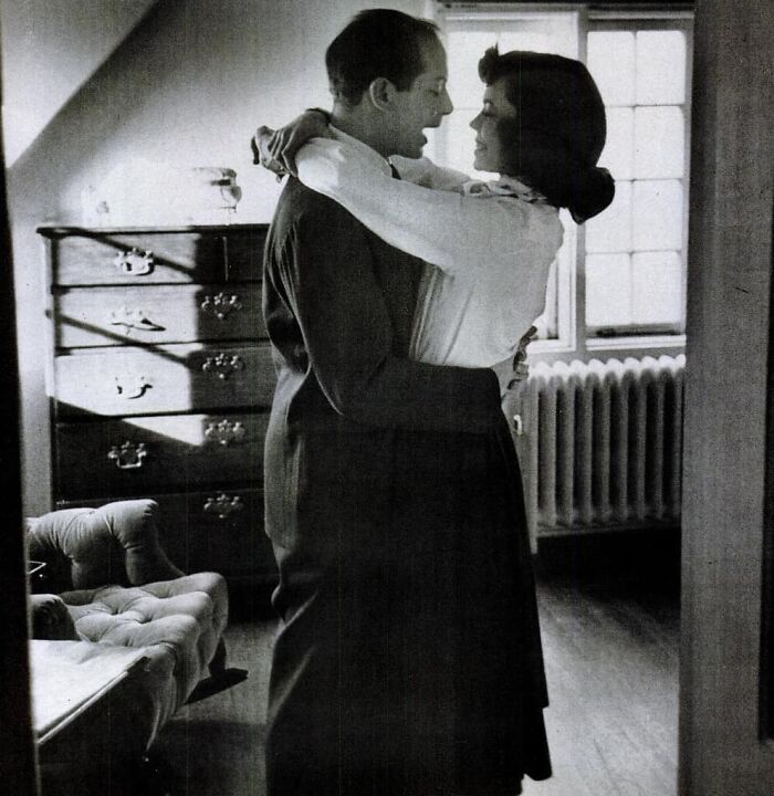 A couple embraces in a vintage room, capturing true happiness by a window.