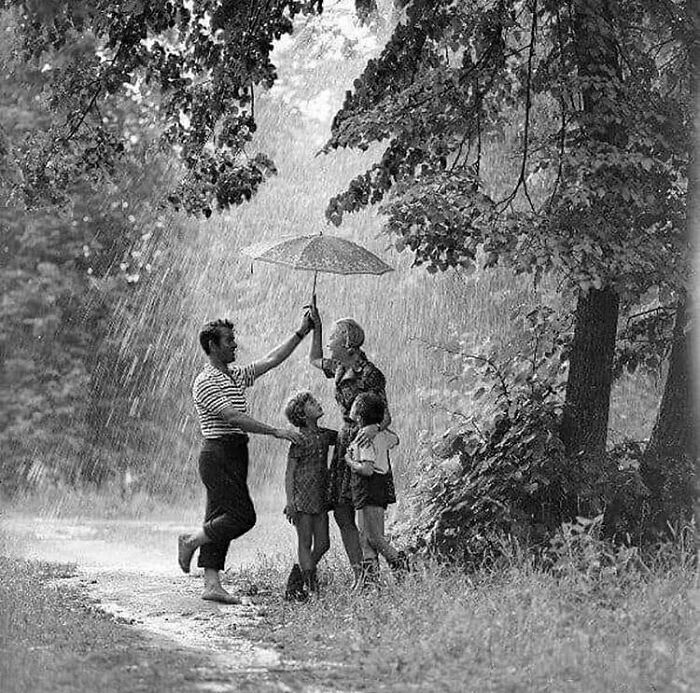 Family huddled under an umbrella in the rain, sharing a magical moment of true happiness.