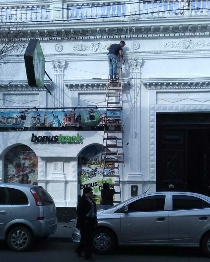 Man on precarious ladder against ornate building facade, illustrating architecture fails risk.