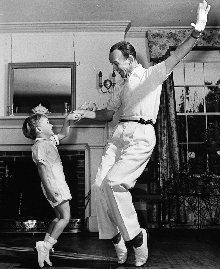 Man and child dancing joyfully indoors, embodying true happiness in a delightful moment.
