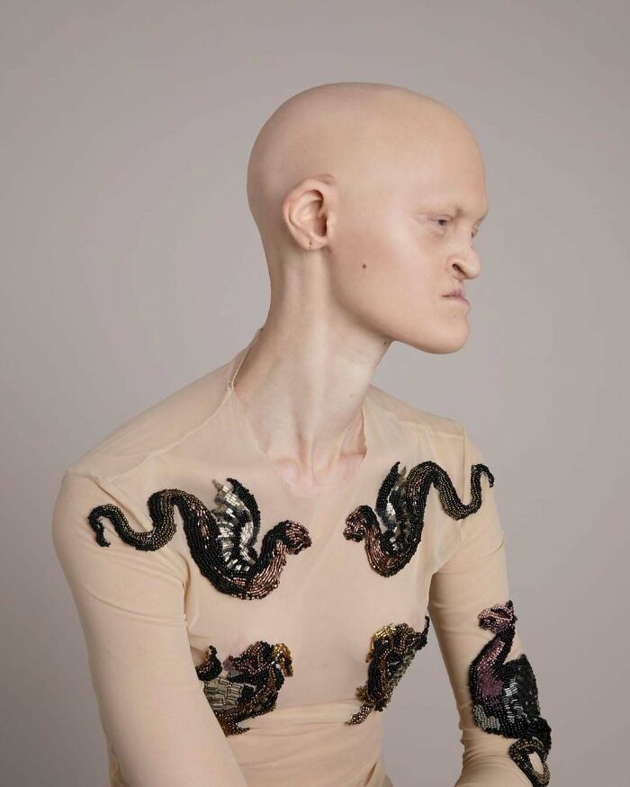 Unique model posing in a sequin-adorned top, showcasing an intricate design against a neutral backdrop.