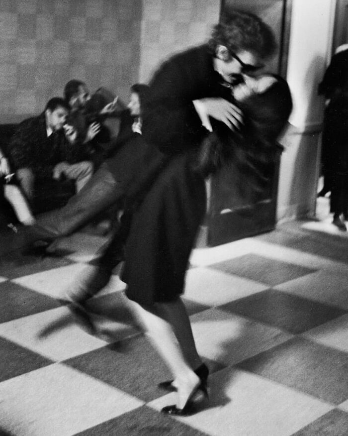 A couple joyfully dancing, capturing true happiness in a blurred motion on a checkered floor.