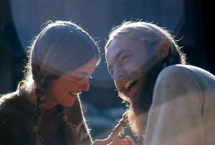 A joyful couple shares a sincere laugh, embodying true happiness in a sunlit moment.