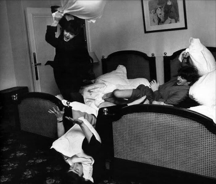 A joyful pillow fight captures true happiness among friends in a hotel room.