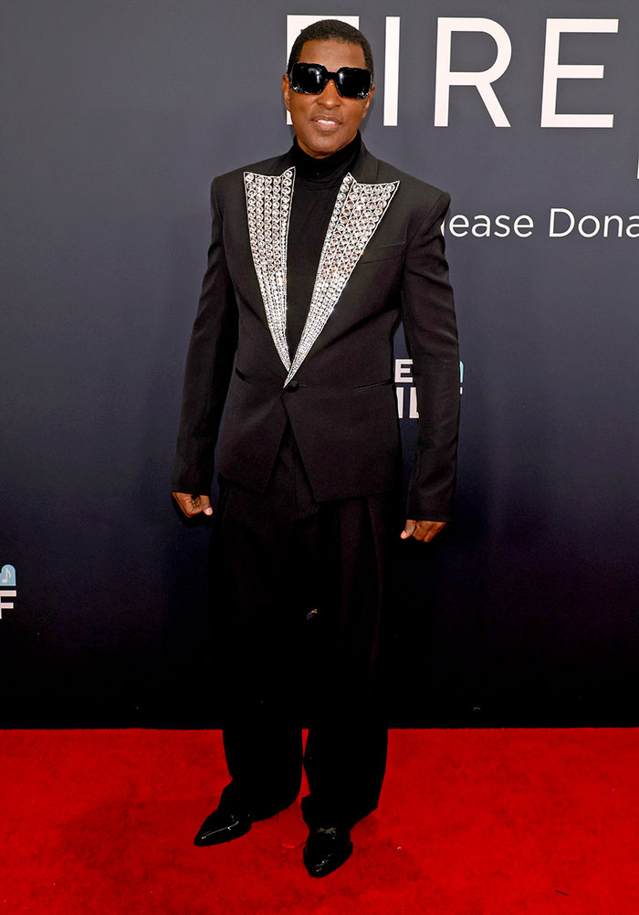 Man in a black suit with sparkling details and sunglasses on the Grammy Awards red carpet.