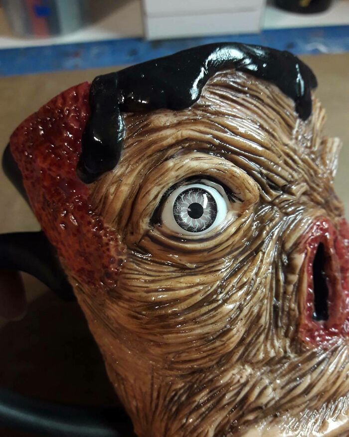 Creepy handmade craft featuring a detailed ceramic face with an exaggerated eye and textured skin.