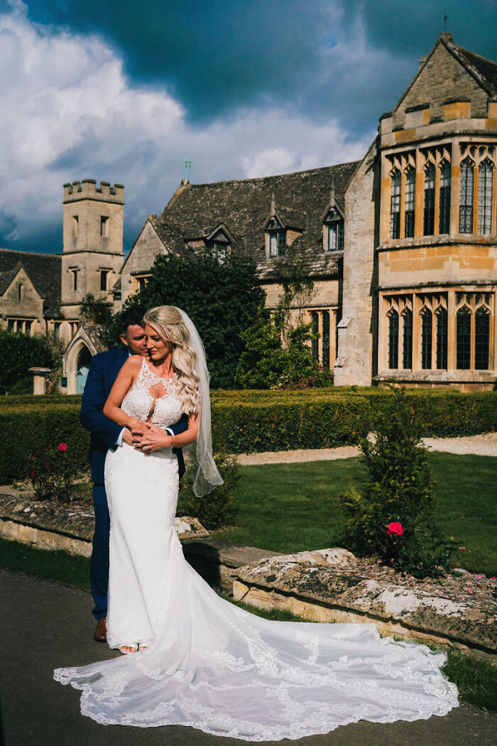 Bride and groom embrace in front of a historic stone building, captured in a best wedding photograph.