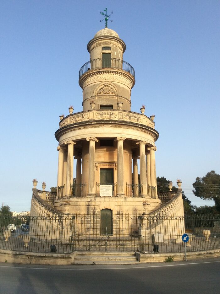 Ornate architectural structure with columns, an example of beautiful useless buildings under a clear blue sky.