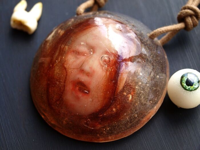 Creepy handmade craft featuring a suspended face in resin alongside a false eyeball.