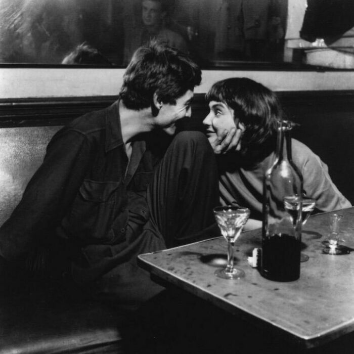 Couple sharing a joyful moment in a cozy setting, capturing true happiness with glasses and a bottle on the table.
