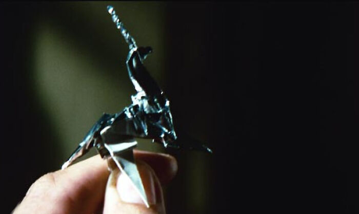 A hand holding a famous movie prop: a small origami unicorn, significant in film storytelling.