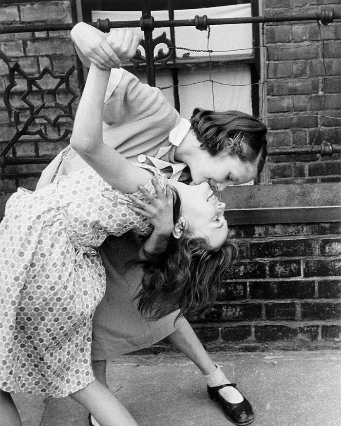 Two children happily dancing together on a sidewalk, capturing true happiness.