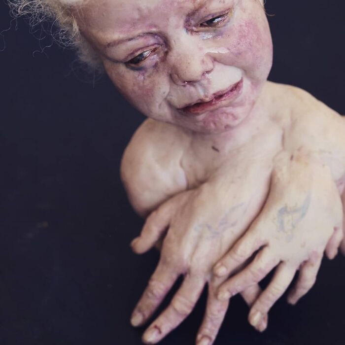 Creepy handmade craft of a doll with multiple hands and an expressive face.