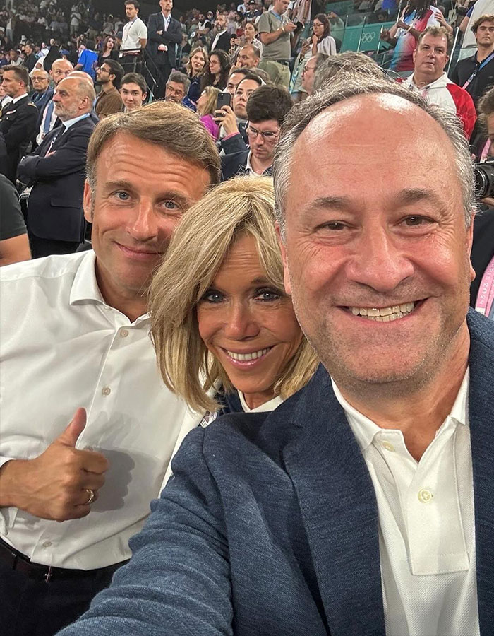 Three people taking a selfie at a crowded event, smiling at the camera, relating to French President's wife.