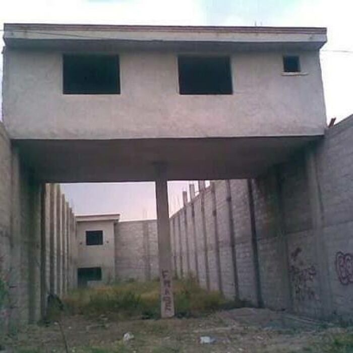 Architecture fail showing a building integrated awkwardly between walls with a narrow support column.