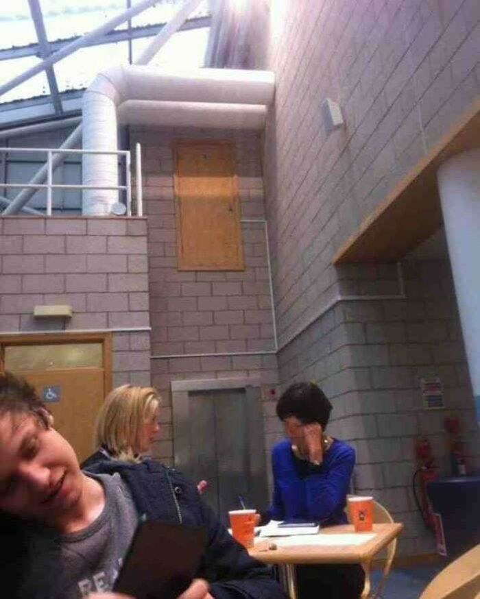 Architecture fail showing a door leading to nowhere, with people sitting nearby in a building's interior.