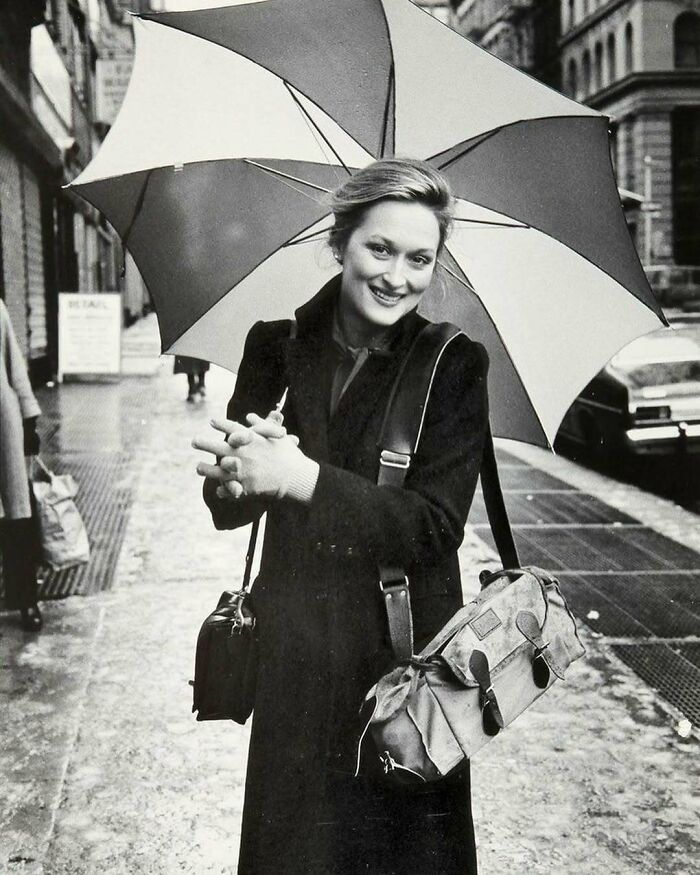 Smiling person holding an umbrella on a city street, capturing true happiness in a candid moment.