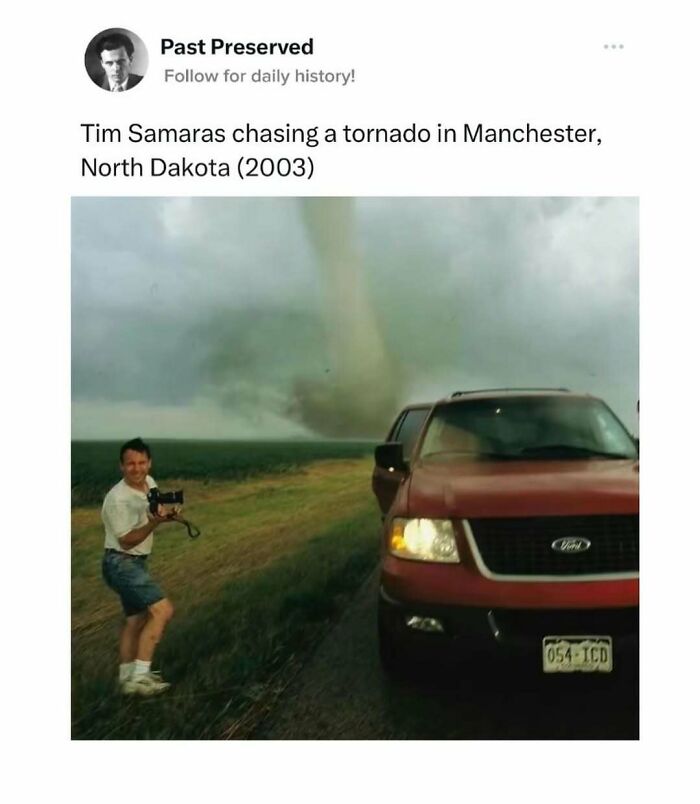Man photographing a tornado with a red truck nearby, North Dakota, illustrating preserved past events.