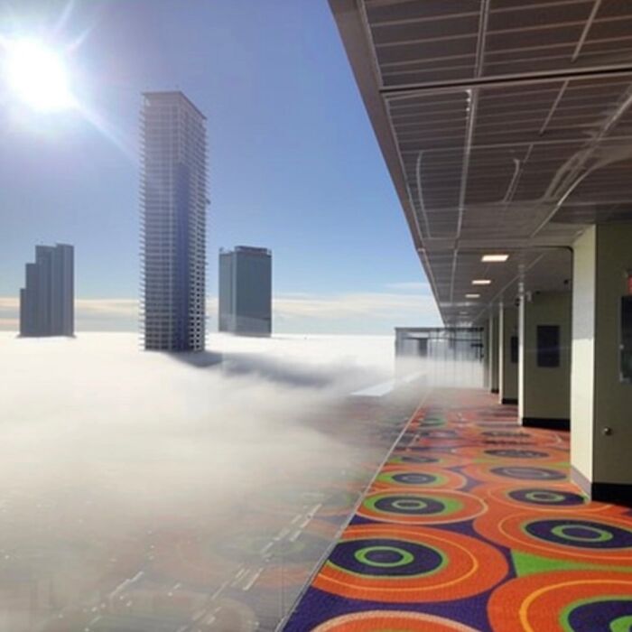 Colorful carpeted corridor high above a foggy cityscape, showcasing a liminal space feeling with distant skyscrapers.