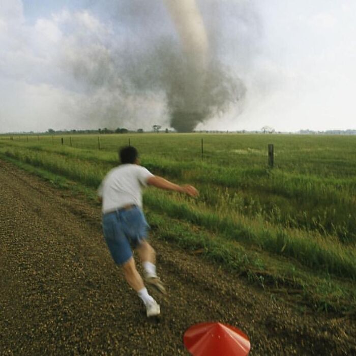 A person running down a road towards a tornado in a field, showcasing the strange aspects of the internet.