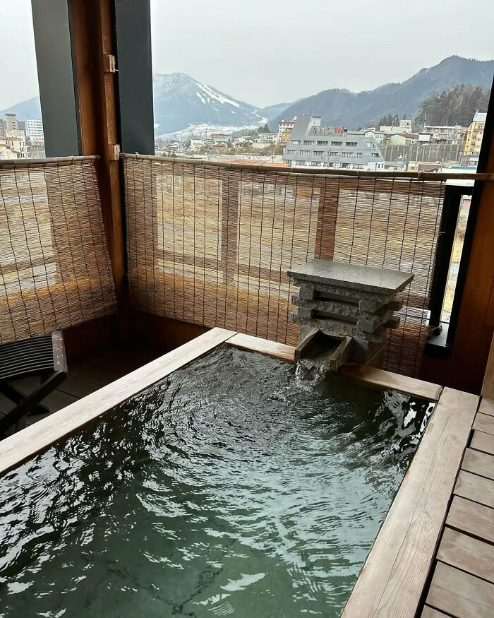 Outdoor hot spring bath with mountain view in Japan, showcasing serene scenery and traditional design elements.