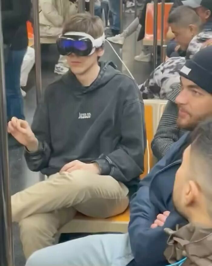 Person wearing VR headset on public transport, highlighting strange internet moments.