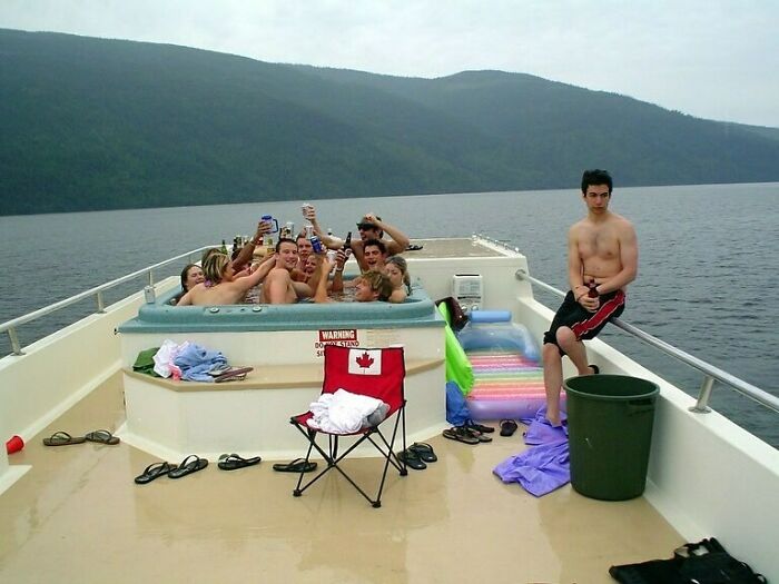 People in a hot tub on a boat, with one person standing apart, embodying strange internet humor.
