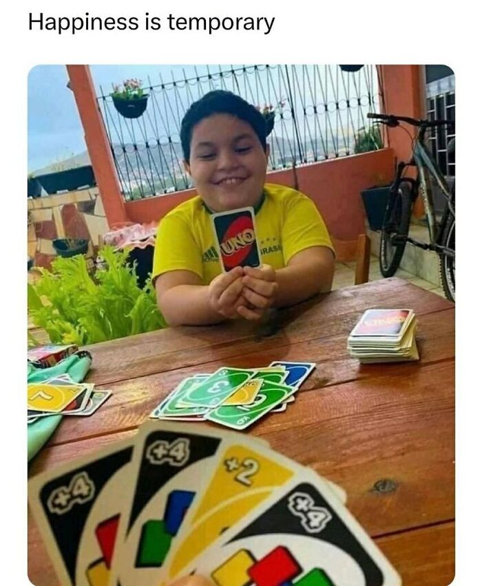 Child amused while playing UNO with humorous card setup.
