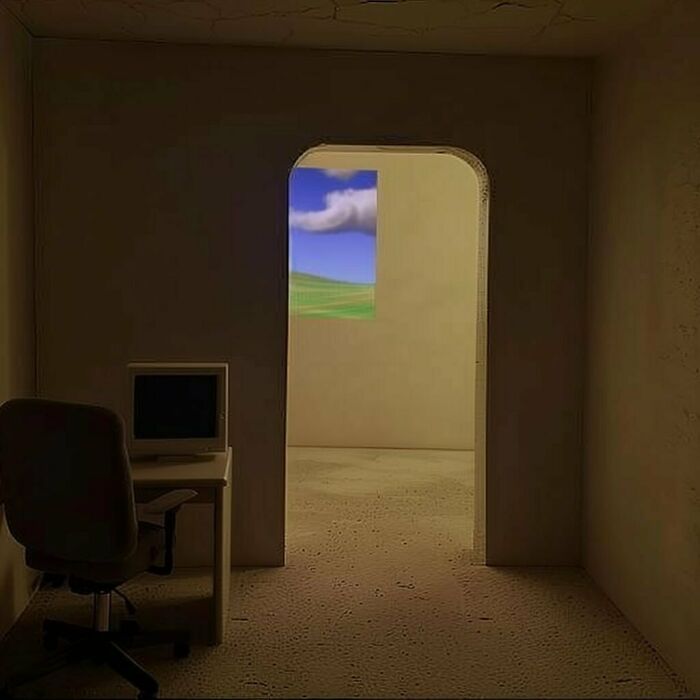 Dimly lit room with a computer desk and a chair, leading to a brightly lit liminal space with a scenic window view.