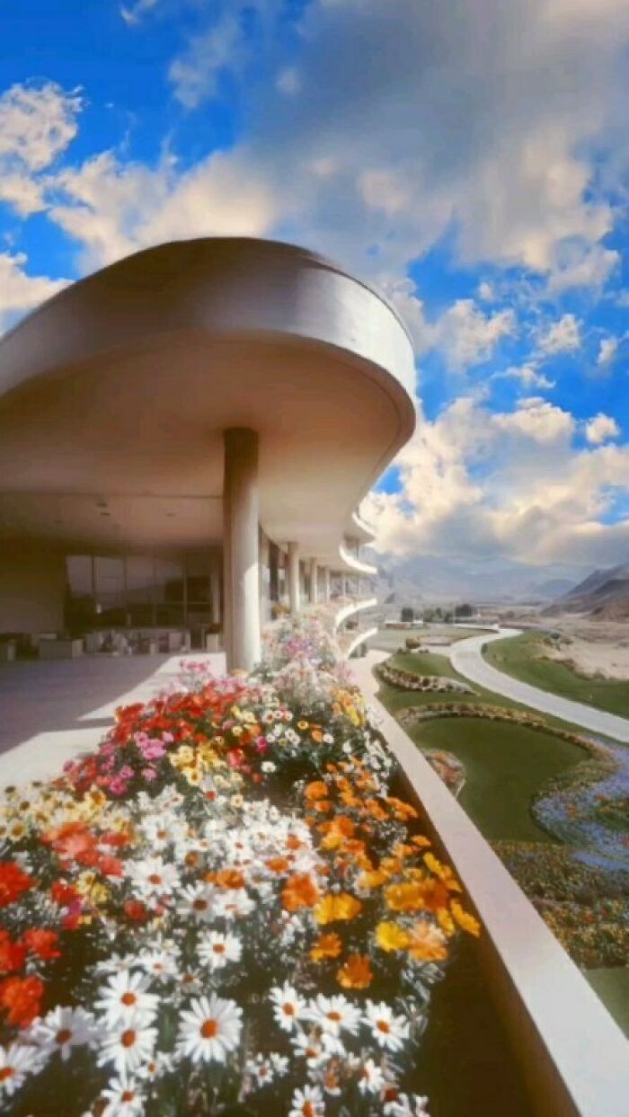 Curved modern building with colorful flowers and a vast, open landscape, exemplifying liminal spaces and solitude.