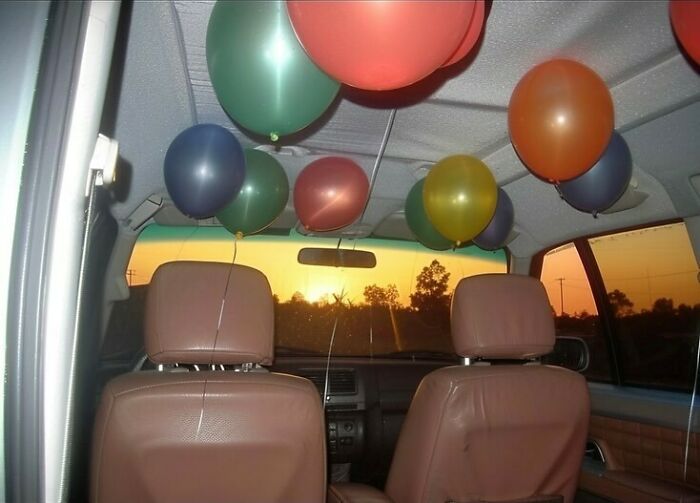 Balloons inside a car at sunset create an eerie liminal space atmosphere.