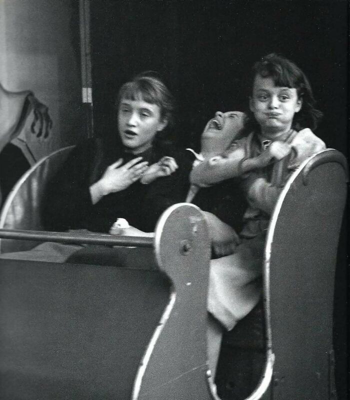 Three people laughing and smiling on a roller coaster, capturing true happiness.