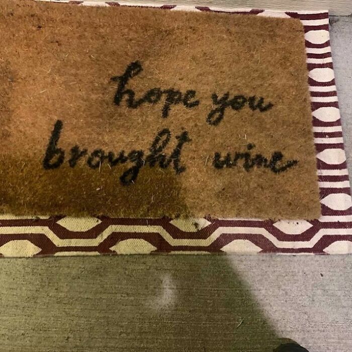 Door mat design fail with the text "hope you brought wine" on a patterned rug.