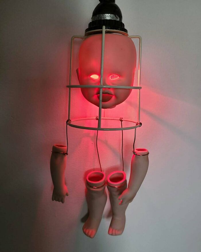 Creepy handmade craft featuring a doll's head and limbs illuminated by a red light.