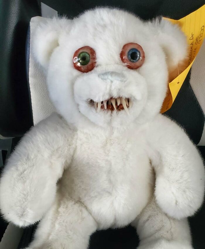 Creepy handmade craft of a plush bear with mismatched eyes and sharp teeth.