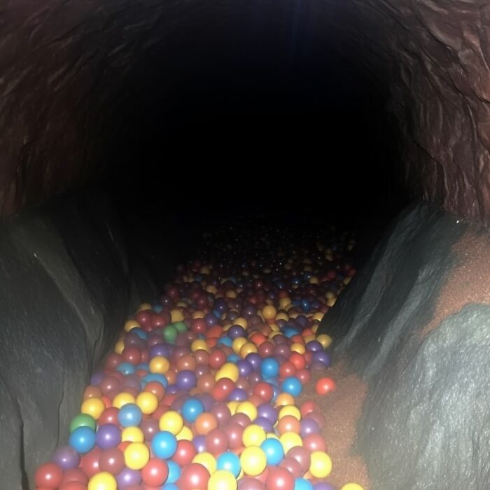 Dark liminal space filled with colorful plastic balls, creating an unsettling atmosphere.