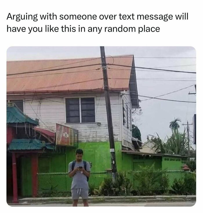 Man standing in front of a house, engrossed in his phone, illustrating hilariously random memes scenario.