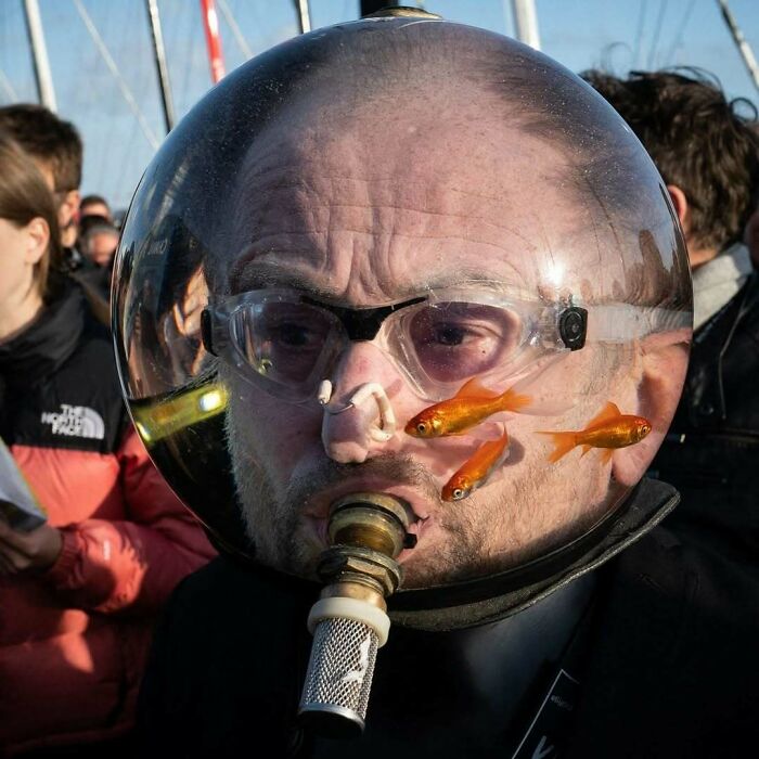 Man with a fishbowl helmet, featuring goldfish swimming, showcasing the internet's strange nature.