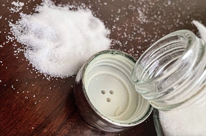 Spilled salt superstition depicted with an overturned salt shaker on a wooden table.