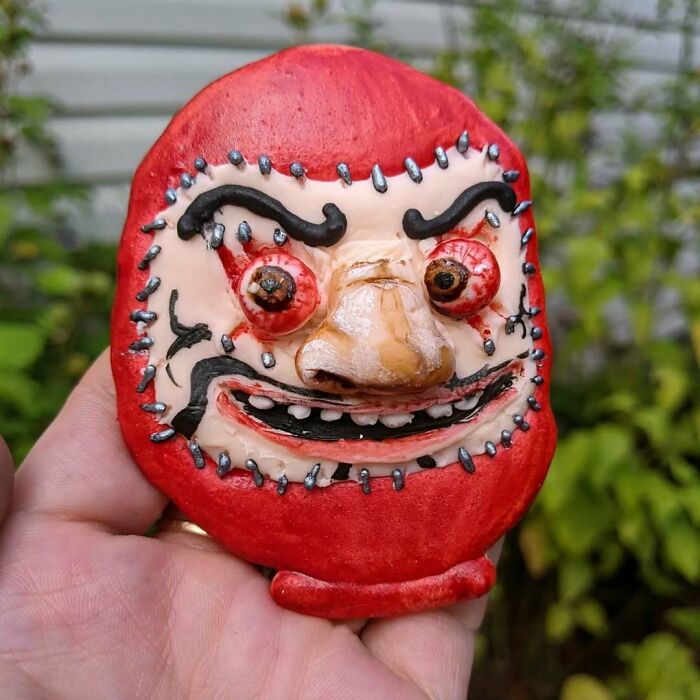 Creepy handmade craft with a vivid red mask featuring exaggerated facial features.
